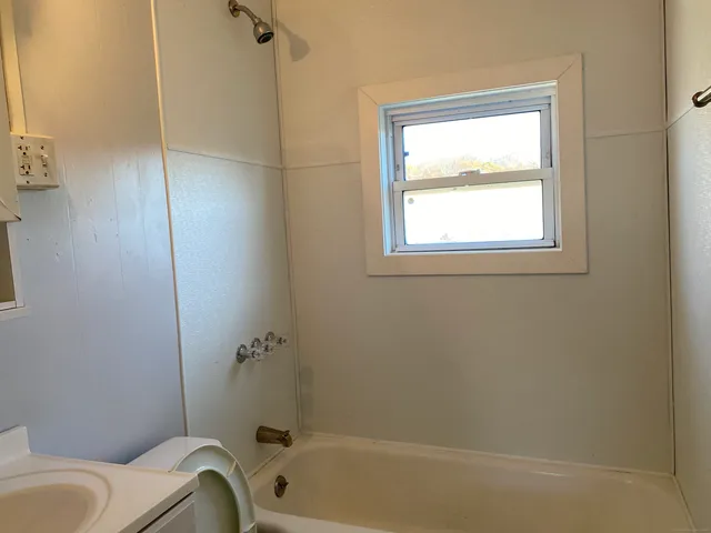 a bathroom with a granite countertop bathtub sink and toilet