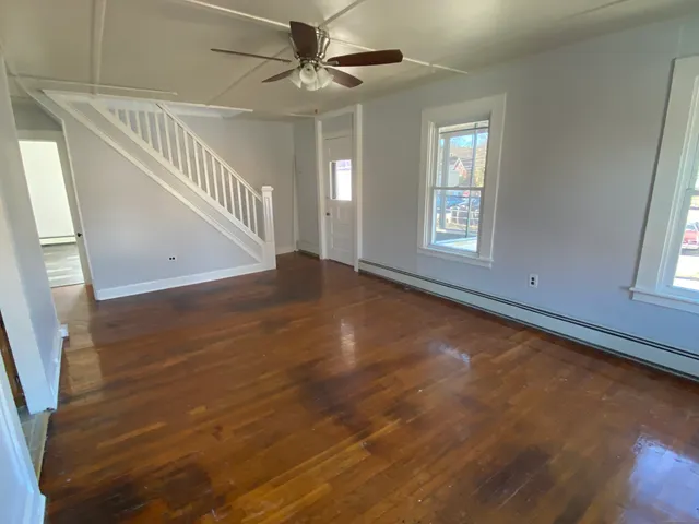 a view of an empty room with a window and wooden floor