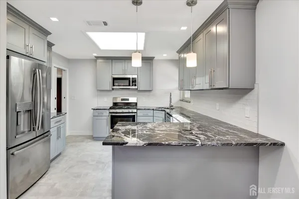 a kitchen with kitchen island granite countertop a stove refrigerator and a sink