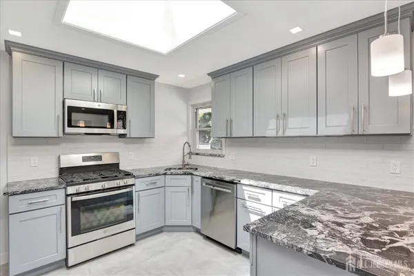 a kitchen with granite countertop white cabinets and stainless steel appliances