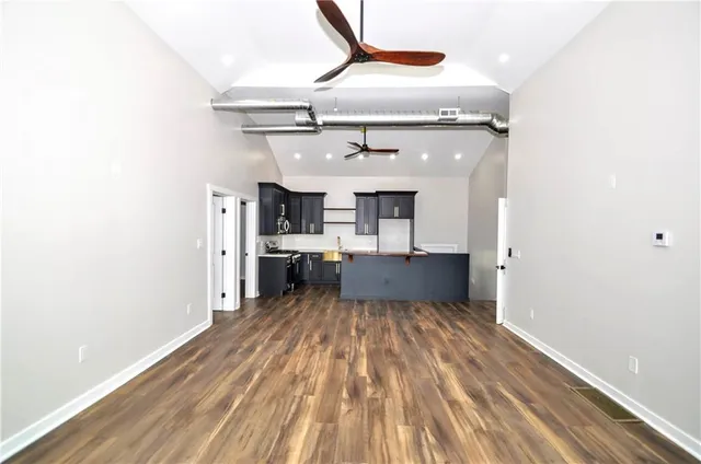 a kitchen with stainless steel appliances granite countertop a refrigerator a sink dishwasher a stove and black cabinets with wooden floor