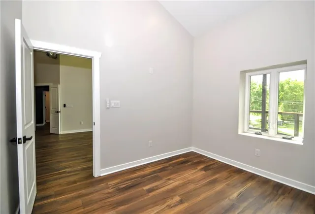 an empty room with wooden floor closet and windows