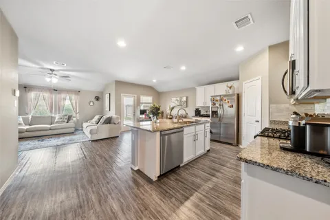 a large white kitchen with lots of counter space a sink and stainless steel appliances