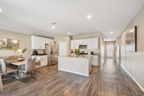 a living room with stainless steel appliances kitchen island hardwood floor and a view of kitchen