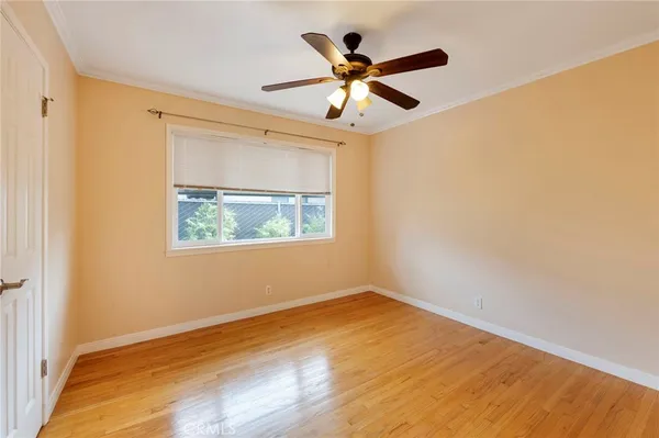 an empty room with wooden floor fan and windows