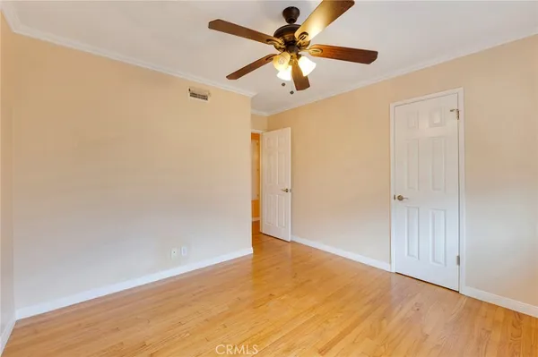 an empty room with wooden floor closet and ceiling fan