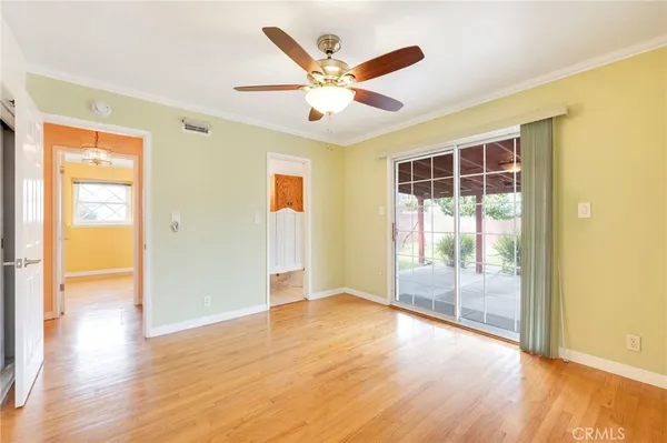 a view of an empty room with wooden floor and a ceiling fan