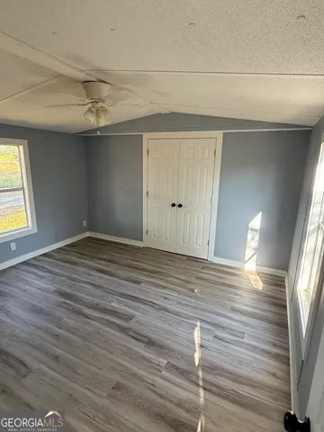 a view of empty room with wooden floor and fan
