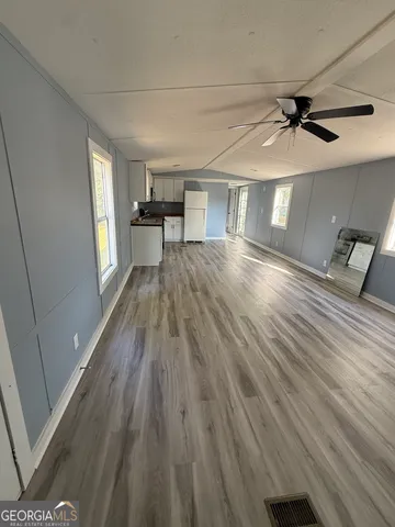 a view of empty room with wooden floor and fan