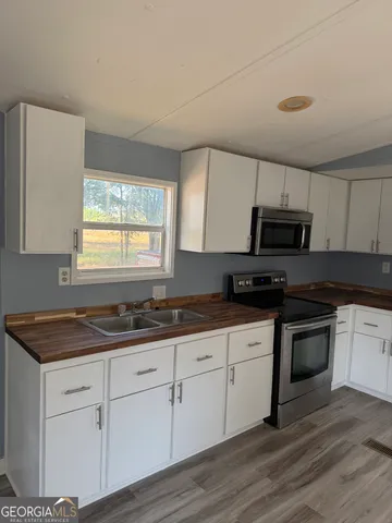 a kitchen with granite countertop white cabinets white appliances a sink and a window