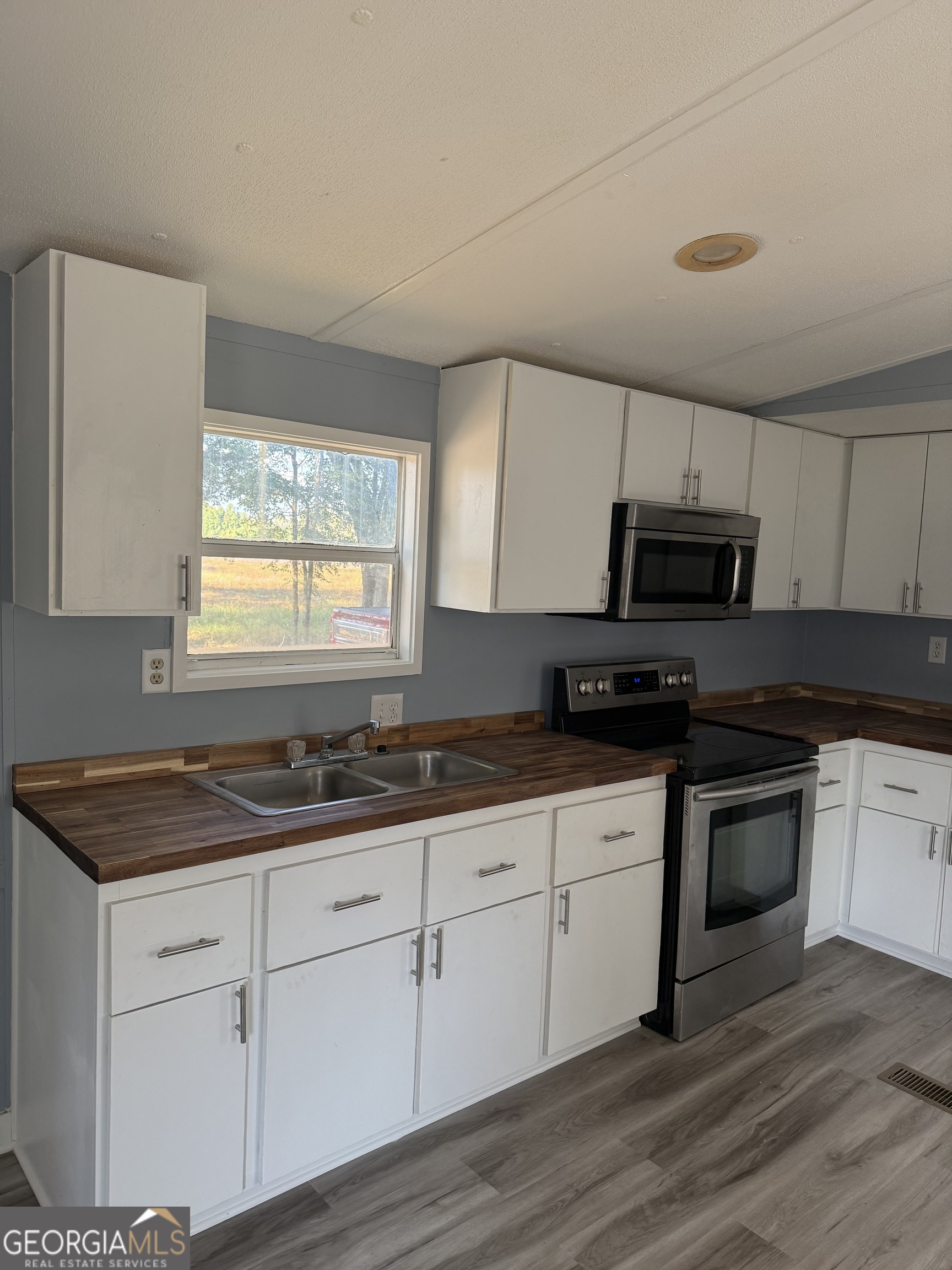 8410 Hawkinsville Road Macon, GA 31216 - Photo 7 of 22 a kitchen with granite countertop white cabinets white appliances a sink and a window