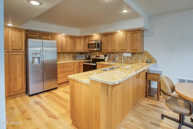 a kitchen with stainless steel appliances granite countertop a sink a stove a refrigerator and island