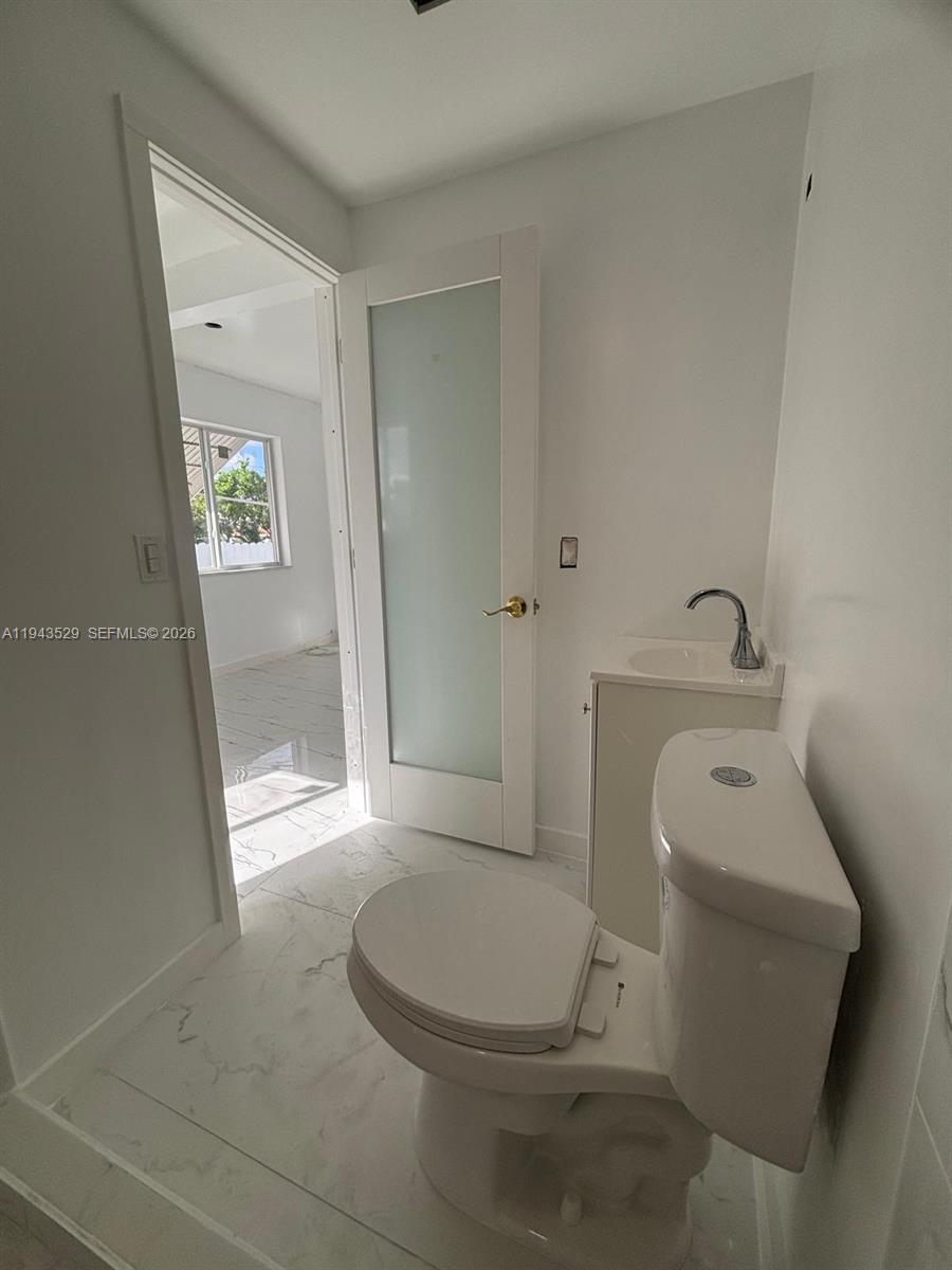 4380 Southwest 1st Street, Unit 1 Miami, FL 33134 - Photo 7 of 10 a white toilet sitting next to a bathroom sink