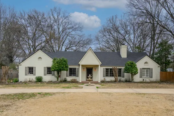 a front view of a house with a garden and tree