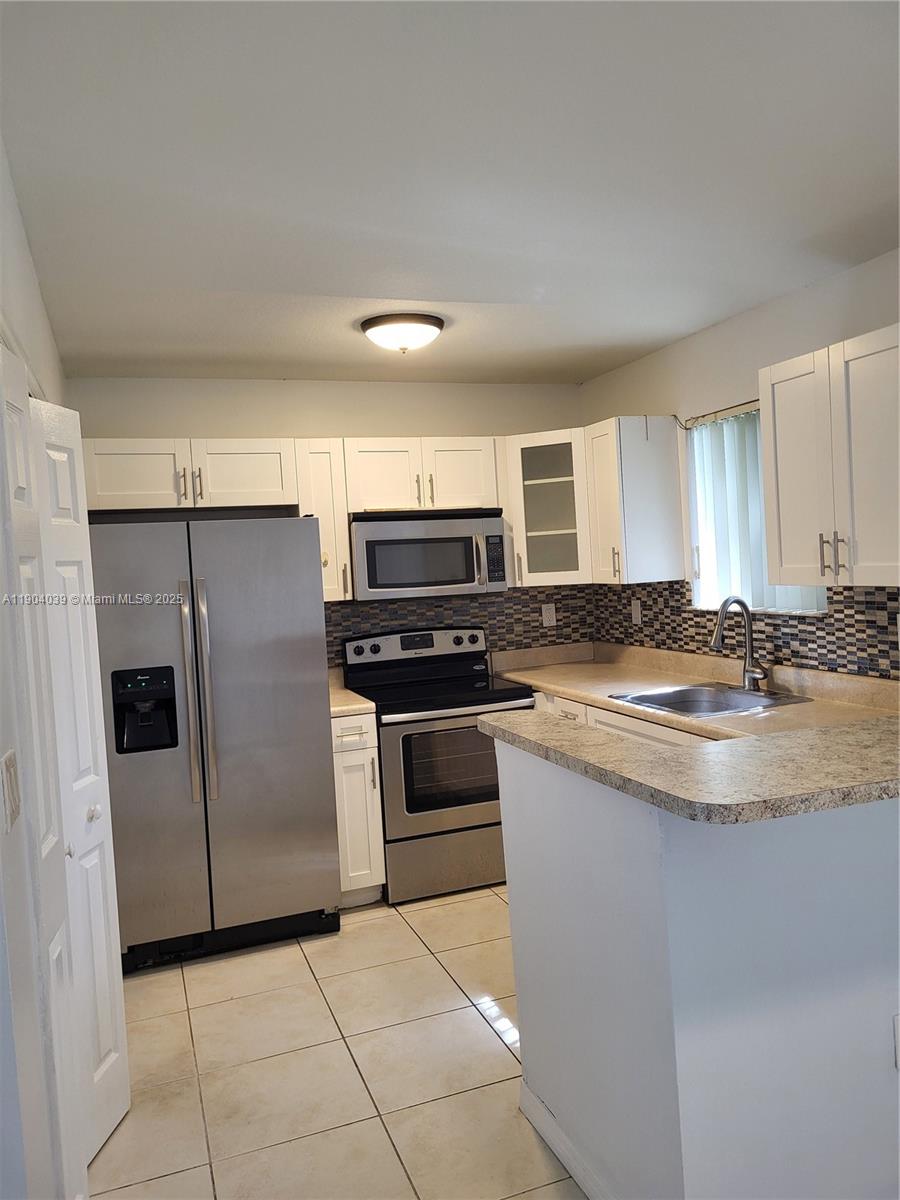 1240 Southeast 28th Court, Unit 201 Homestead, FL 33035 - Photo 6 of 10 a kitchen with granite countertop a refrigerator and a stove top oven