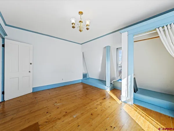 a view of an empty room with window and wooden floor
