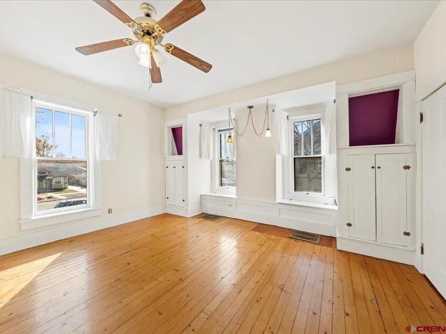 a view of empty room with wooden floor and fan