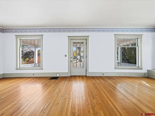 a view of an empty room with wooden floor and a window