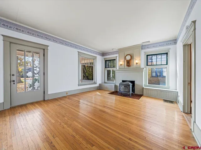 a view of an empty room with wooden floor fireplace and a window
