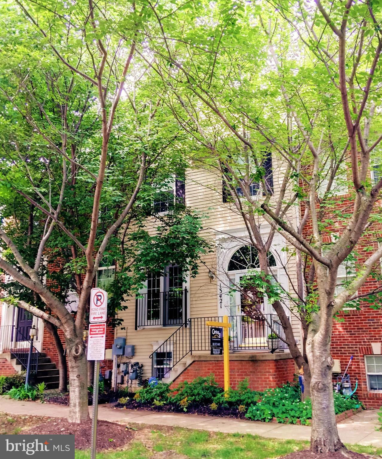 front view of a house with a tree and plants