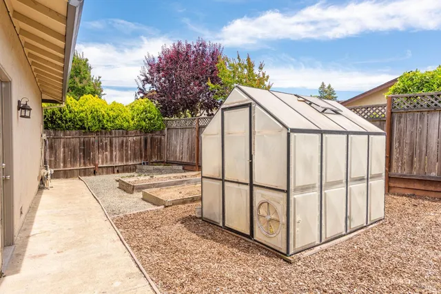 a view of a white house with a small yard and large trees