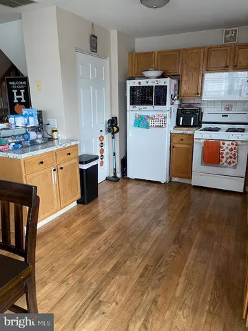 a kitchen with stainless steel appliances a stove a sink cabinets and a wooden floor