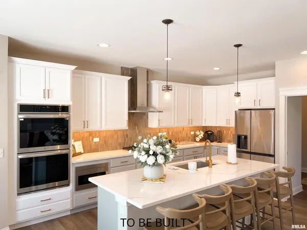 a kitchen with stainless steel appliances kitchen island granite countertop a dining table chairs and a refrigerator