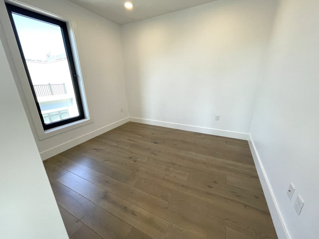 30 Penniman Road, Unit 507 Boston, MA 02134 - Photo 7 of 22 an empty room with wooden floor and windows