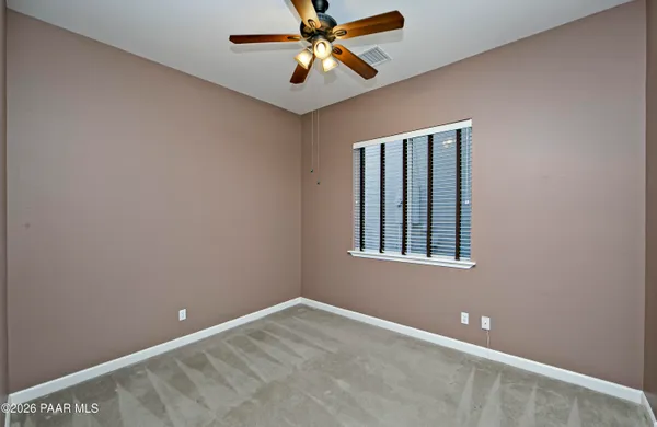 a view of an empty room with window and a ceiling fan