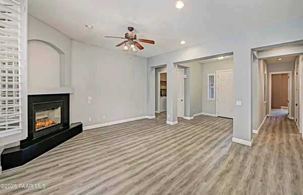 a view of an empty room with wooden floor fireplace and a window
