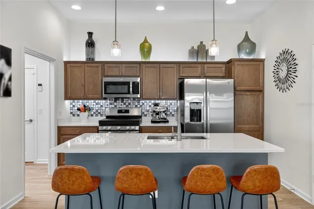 a kitchen with stainless steel appliances granite countertop a sink a microwave a refrigerator and chairs