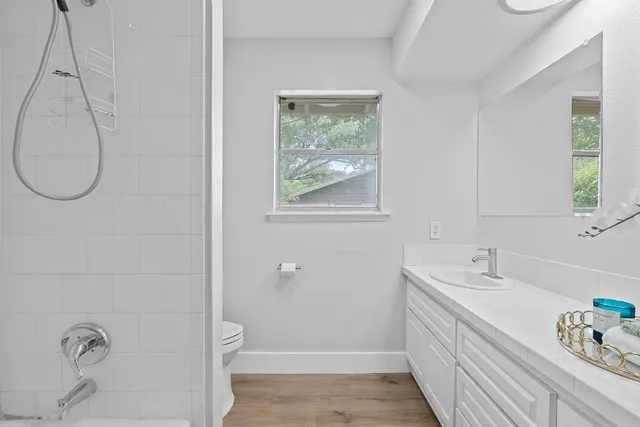 a bathroom with a granite countertop sink a toilet and a window