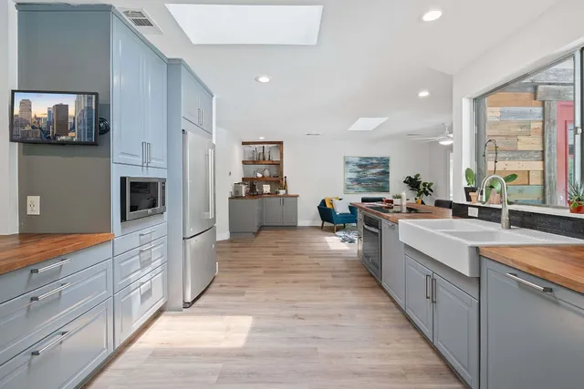 a large kitchen with stainless steel appliances a large counter top a stove a sink and a refrigerator