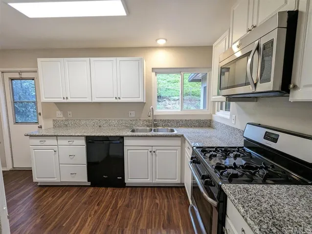 a kitchen with granite countertop wooden cabinets stainless steel appliances and a window
