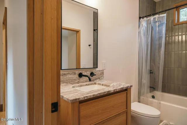 a bathroom with a granite countertop sink toilet and shower