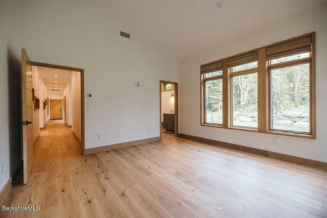 a view of an empty room with window and wooden floor
