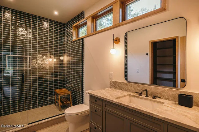 a bathroom with a granite countertop toilet a sink a mirror and shower curtain