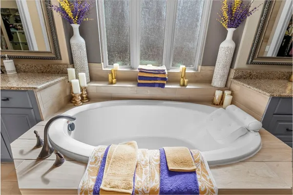 a bathroom with a granite countertop tub sink shower and mirror