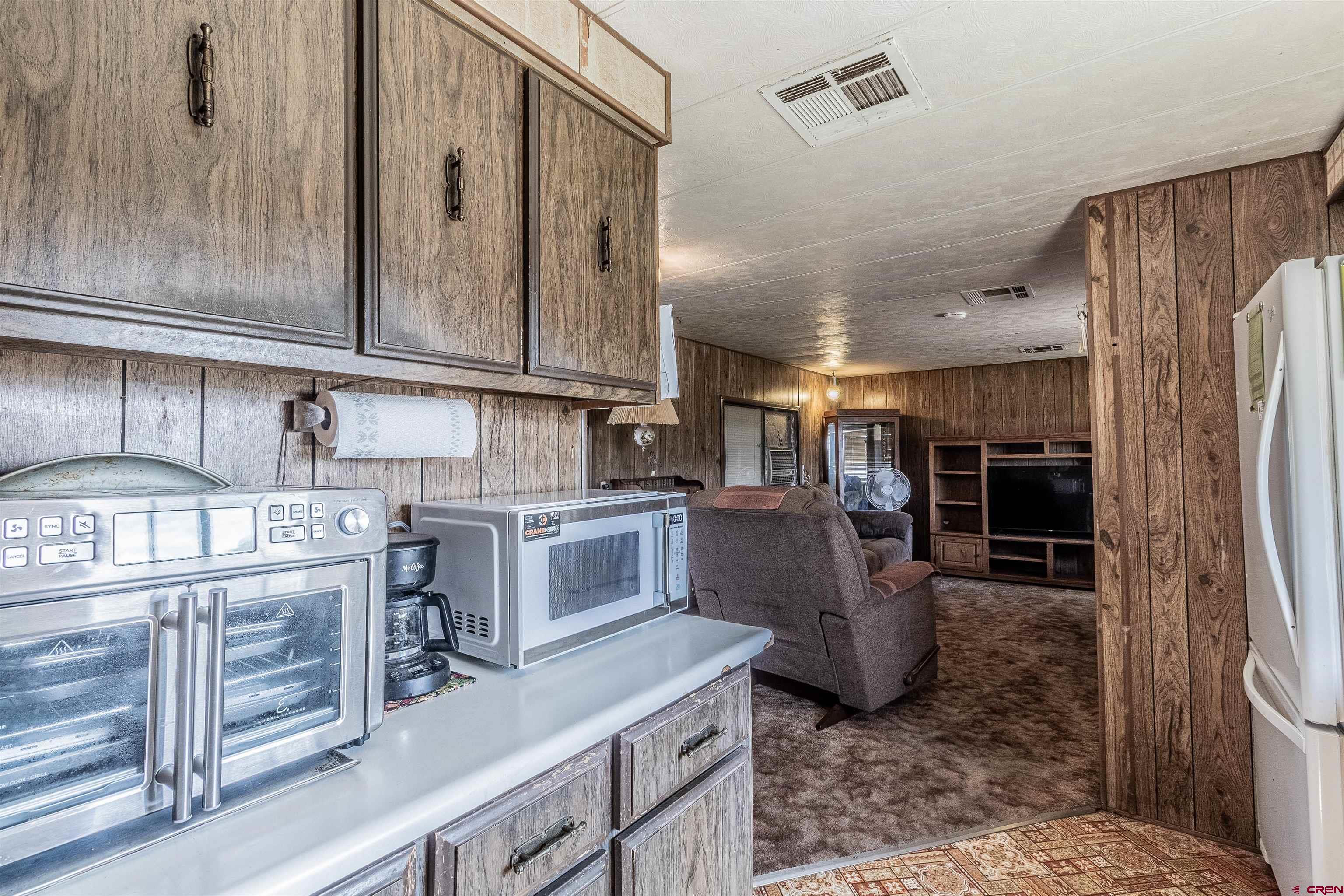 16923 Highway 550 Aztec, NM 87410 - Photo 33 of 45 a kitchen with stainless steel appliances granite countertop a refrigerator a stove and a sink with wooden cabinets