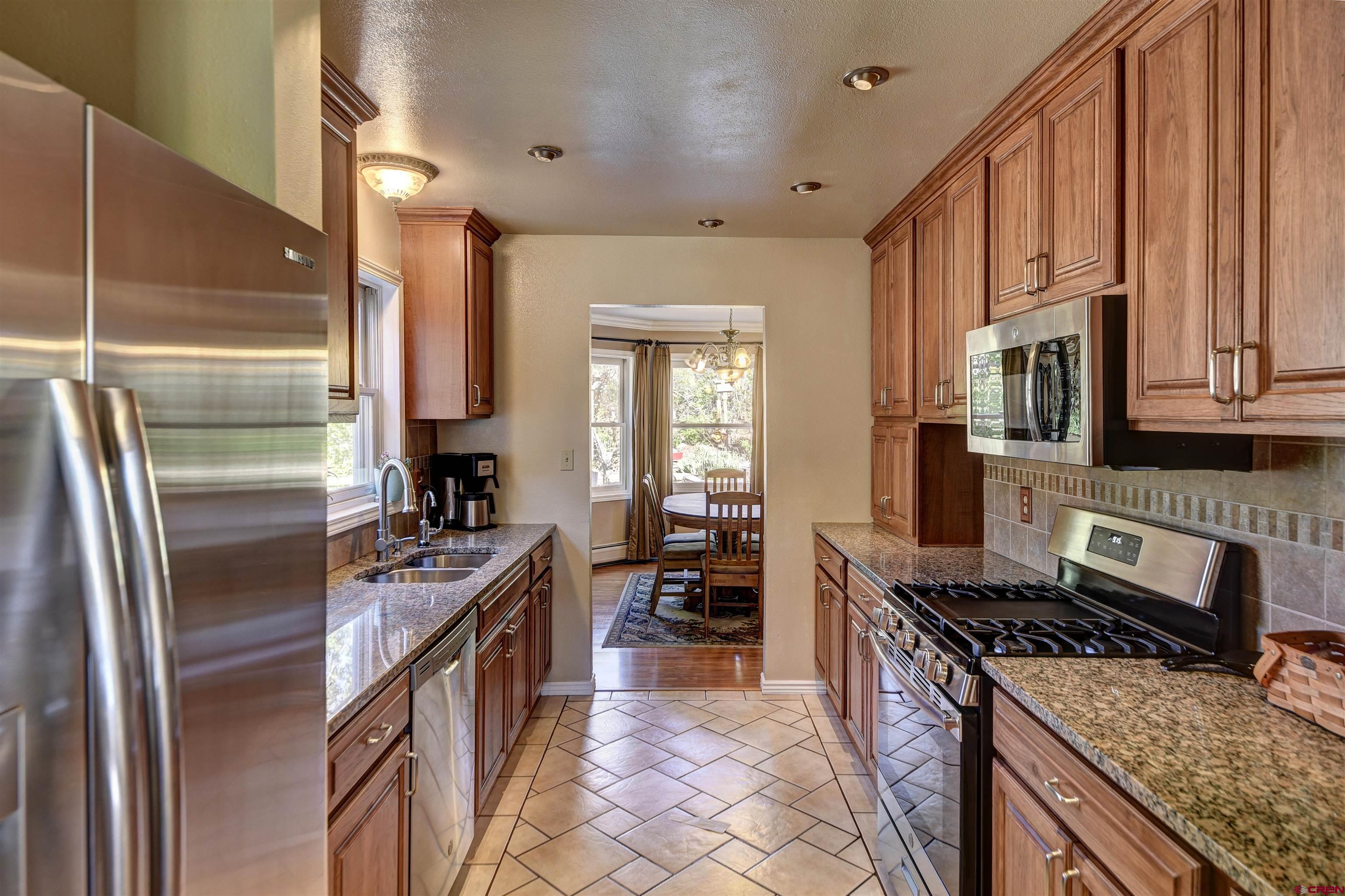 1172 Ridge Road Durango, CO 81303 - Photo 20 of 28 a kitchen with stainless steel appliances granite countertop a stove top oven a sink dishwasher a refrigerator and cabinets with wooden floor