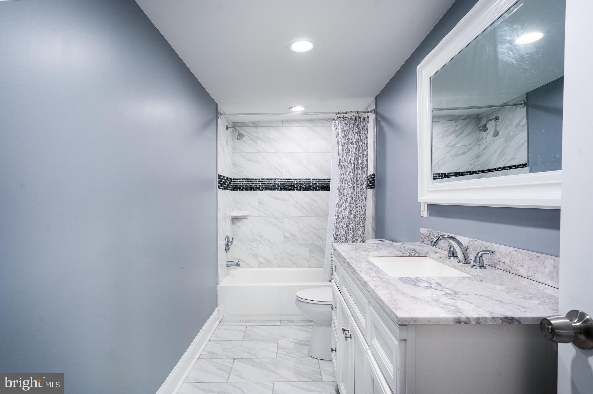 921 Eastern Avenue Baltimore, MD 21202 - Photo 16 of 23 a bathroom with a granite countertop sink a mirror and a shower