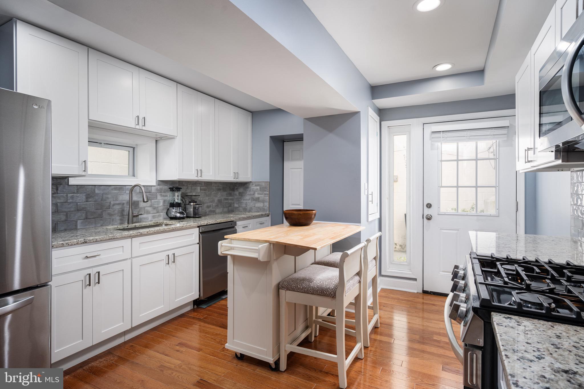 921 Eastern Avenue Baltimore, MD 21202 - Photo 9 of 23 a kitchen that has a lot of cabinets in it with stainless steel appliances granite countertop a stove a sink dishwasher and white cabinets with wooden floor