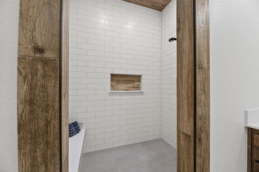 985 Vest Lane Pilot Point, TX 76258 - Photo 26 of 40 Walk-in shower with subway tile walls, wood-finish ceiling, and a built-in shower niche