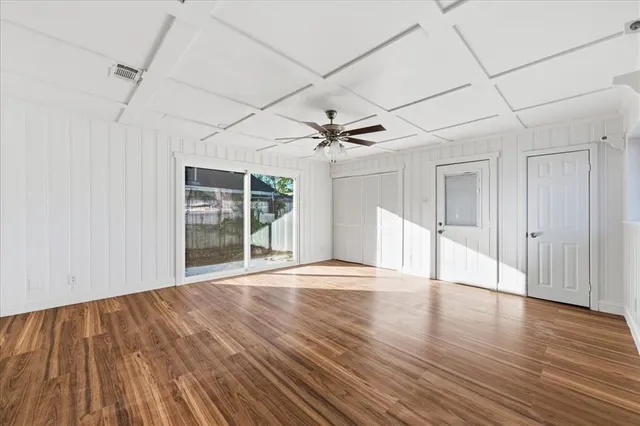 a view of empty room with wooden floor and fan