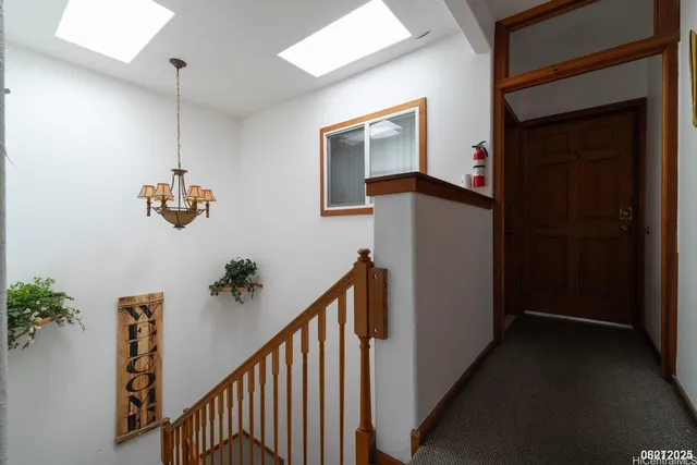 an empty room with wooden floor chandelier fan and windows