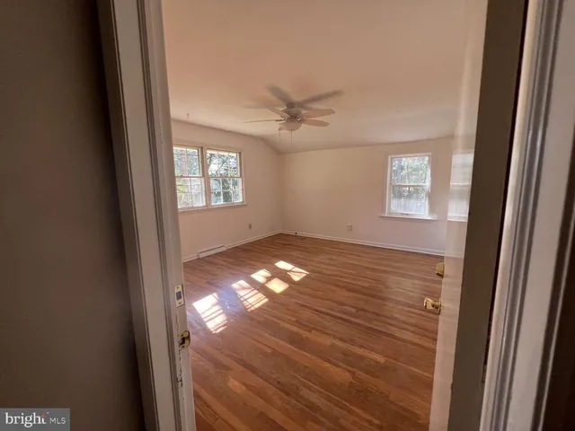 a view of empty room with wooden floor and fan