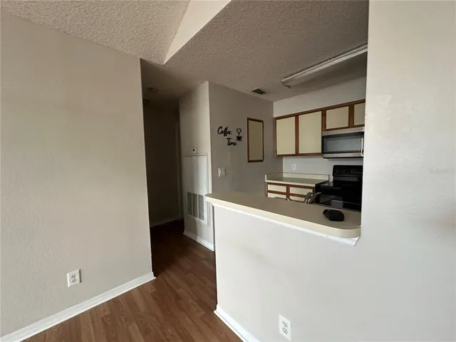 a kitchen with wooden floor and electronic appliances