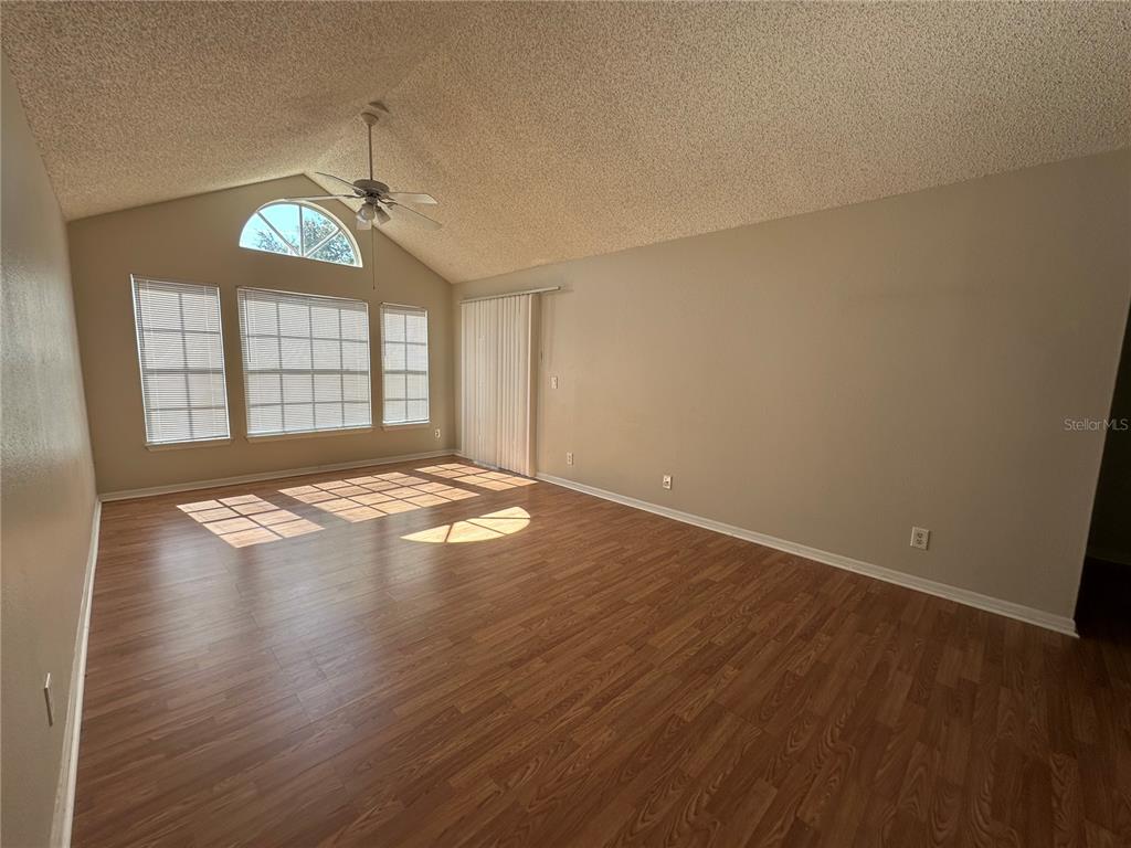 1073 South Hiawassee Road, Unit 1023 Orlando, FL 32835 - Photo 3 of 16 an empty room with wooden floor chandelier fan and windows