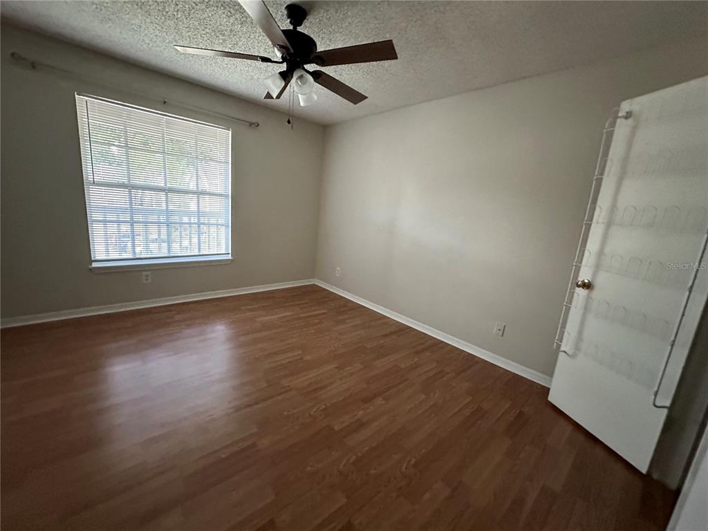 1073 South Hiawassee Road, Unit 1023 Orlando, FL 32835 - Photo 7 of 16 an empty room with wooden floor fan and windows