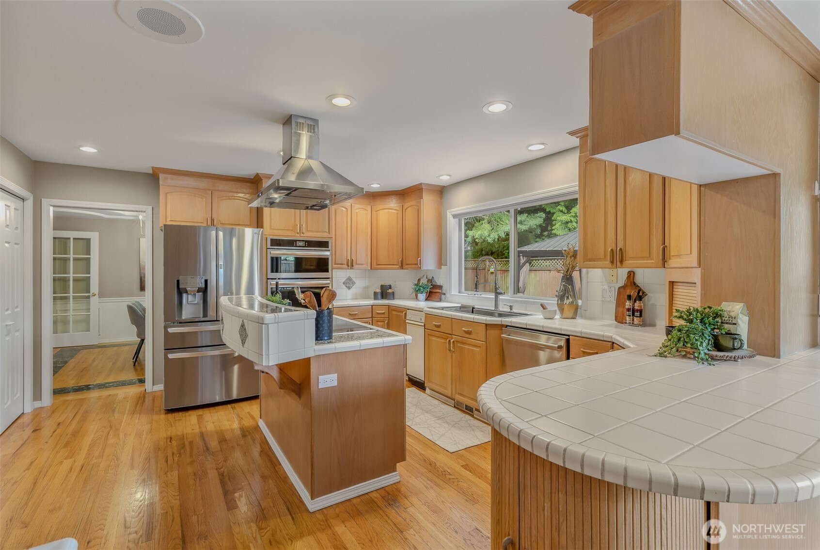 2323 241st Street Southeast Bothell, WA 98021 - Photo 10 of 40 a kitchen with stainless steel appliances kitchen island granite countertop a refrigerator a stove top oven a sink dishwasher and wooden cabinets with wooden floor